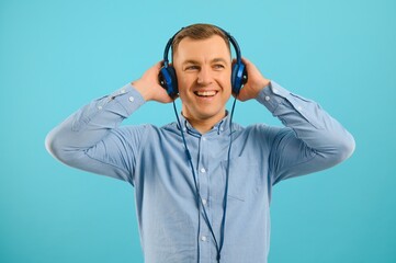 Handsome young man listening to music on color background