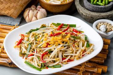 Tumis Tauge ikan asin or Salted Bean Sprouts is one of type traditional cuisine in Indonesia. sauteed bean sprouts cooked with salted fish served on plate and isolated gray background.