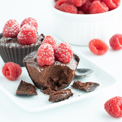 Close up of chocolate cups filled with chocolate mousse topped with raspberries.