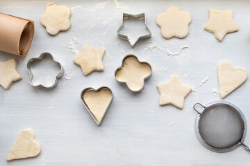 Top view of woman hands cooking a gingerbread cookie in the form of heart, star, cloud and flower. Christmas and New Year concept, festive preparations for winter hilodays
