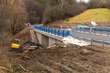 Excavator adjusts the terrain around the new bridge.  Finishing work on the construction of a bridge on a country road in the Czech Republic.