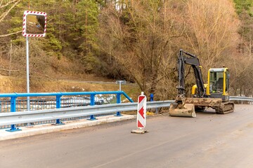 Excavator adjusts the terrain around the new bridge.  Finishing work on the construction of a...