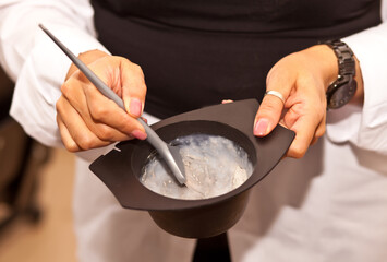Hairdresser barber hands mixing hairdye in bowl