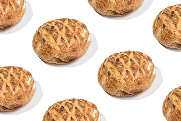 Repetitive pattern with loafs of freshly baked wheat bread on white background. Minimal food background.