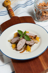 top view, medium distance of Five Spice Pork with Orange and Fennel with sprig of mint on white, ceramic dish with blue rim, on wood serving board