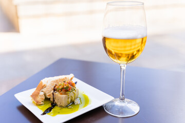 Traditional pintxo made of tuna on bread and beer glass. Restaurant tapa on table, bar snack concept