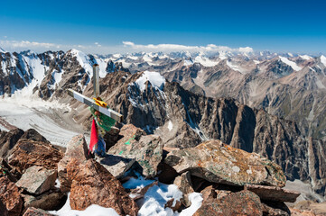 Metal cross with tibetian flags on top of Pik Uchitel peak with cross. Ala Archa Alpine National...