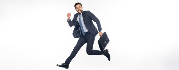 Fototapeta na wymiar positive businessman in suit jumping with briefcase on white, banner.