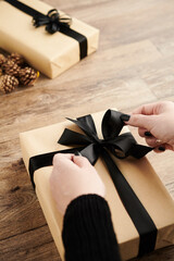 Woman wrapping Christmas presents and decorating with black ribbons