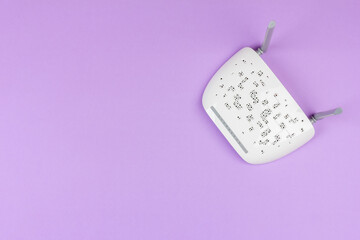 new white Wi-Fi router with gray antennas on a light purple background top view from a copy space