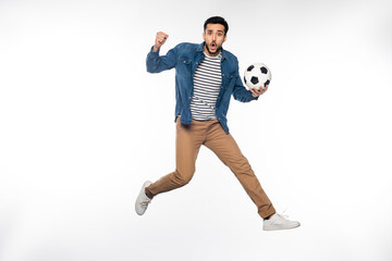 worried man levitating while holding soccer ball and cheering on white.