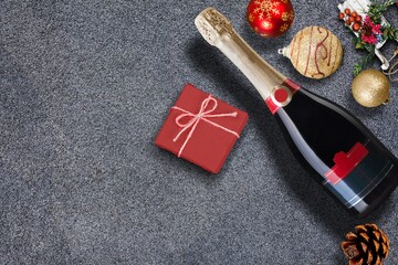 A bottle of red wine with a blank label with Christmas decorations and a gift box on desk.