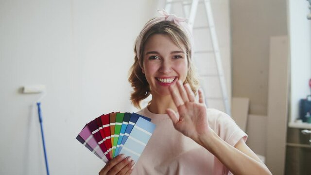 Woman blogger choosing color for painting walls, holding palette of shades, recording video. Overhaul concept and new interior design. Female designer planning color scheme of new flat.