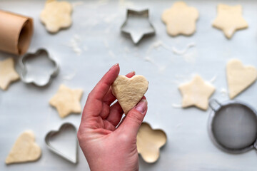 Top view of woman hands cooking a gingerbread cookie in the form of heart, star, cloud and flower. Christmas and New Year concept, festive preparations for winter hilodays
