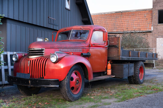 Old red Chevrolet Pick Up from 1942 with wooden loading platform standing in front of a shed