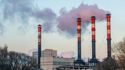 Obraz premium Smoking pipes from factories against a sunset sky. Close-up view of smoking factory chimney. Ecological problem.
