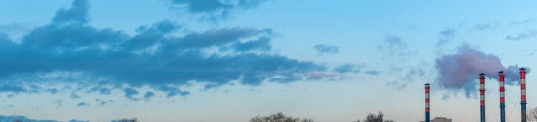 Smoking pipes from factories against a sunset sky. Close-up view of smoking factory chimney. Ecological problem.