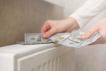 dollar bills in female hands on the background of a radiator close-up.