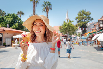 Cheerful woman with a snow-white smile eats delicious ice cream and rests in a resort town by the...