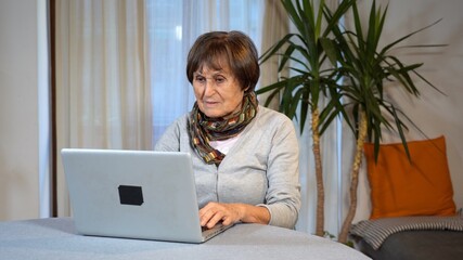 Old senior woman 70 years old at home sitting on sofa during Covid-19 Coronavirus lockdown...