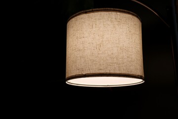 Floor lamp lit with warm shade against black background