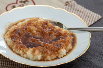 Creamy rice pudding with cinnamon and sugar in plate served. french milk rice dessert with cinnamon rice pudding. also Risgrynsgröt. Swedish rice pudding
