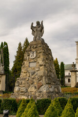 Monument next to the church surrounded by trees and alleys. - obrazy, fototapety, plakaty