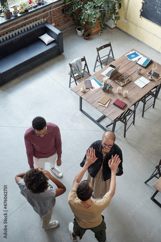 Poster two young co-workers touching by hands while their colleagues having chat at break against table and