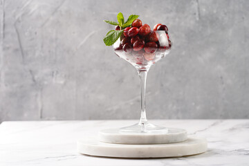 Wide champagne glass filled with fresh raw cranberries on a round marble tray