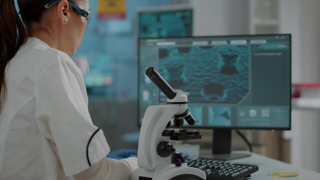 Biology scientist working with microscopic tool in laboratory, analyzing dna substance with optical lens. Chemist using microscope with magnifying glass for scientific development.