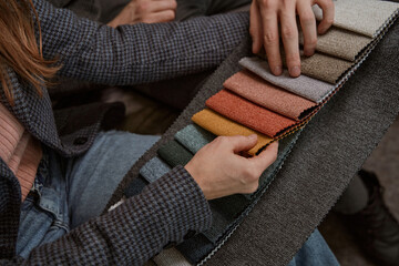 Two Caucasian buyers examining fabric samples for sofa