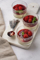 Italian dairy dessert panna cotta with raspberry jam, fresh raspberries and mint on marble board
