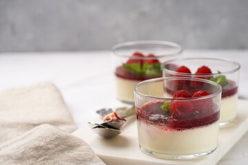 Italian dairy dessert panna cotta with raspberry jam, fresh raspberries and mint on marble board
