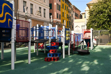 Fototapeta na wymiar Empty free playground in the Molo quarter, near the Old Port, with colorful playing structures between ancient houses, Genoa, Liguria, Italy