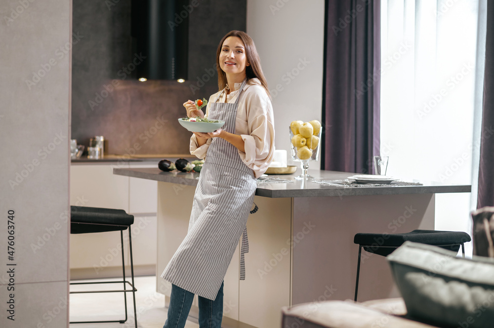 Wall mural young long-haired woman with plate in hands in the kitchen