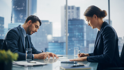 Female and Male Business Partners Sign Successful Deal Documents in Meeting Room Office. Corporate...