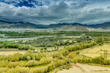 Aerial view of Leh City, green landscape with ice peaks , blue sky with clouds in background , Ladakh, Jammu and Kashmir, India.