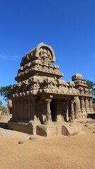 This is "five rathas" as they resemble the processional chariots of a temple. Statues carved in rock. this is one features in several Hindu scriptures. blue sky backgrounds