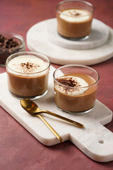 Italian chocolate and coffee mousse dessert semifreddo - half-frozen ice cream with whipped cream and cocoa powder in small glasses on purple surface