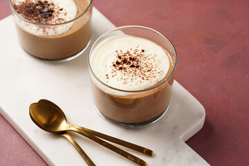 Italian chocolate and coffee mousse dessert semifreddo - half-frozen ice cream with whipped cream and cocoa powder in small glasses on purple surface