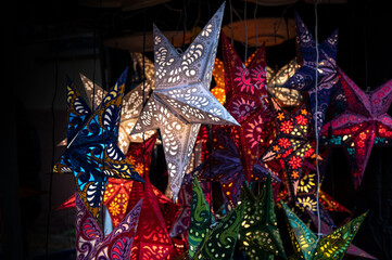 Shining Christmas stars folded from paper in different colors in a market stall, lantern for the...