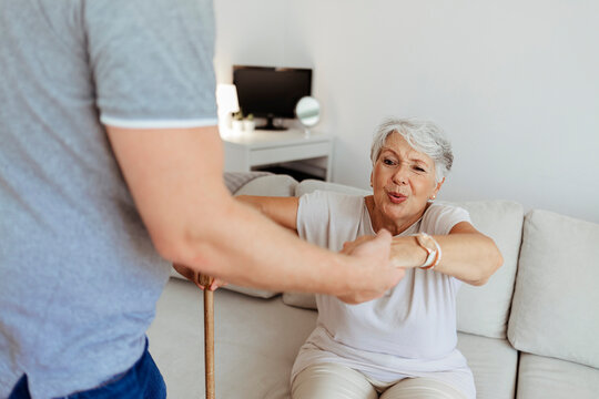 Close up of male carer holding hands of senior woman, home caregiver showing support for elderly patient. Cropped image of male professional caregiver taking care of elderly woman at home.
