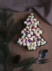 festive beautiful cake in the form of a spruce on a wooden background with marshmallows and spruce branches