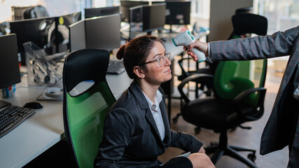 Doctor measures the temperature of an office worker with an infrared thermometer. 
