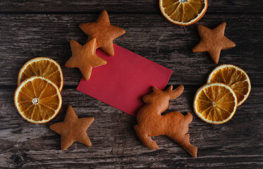 ginger cookies in the form of deer and stars with orange slices on a wooden background with a copy space