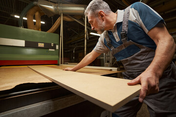 Concentrated grey-haired man standing close to equipment