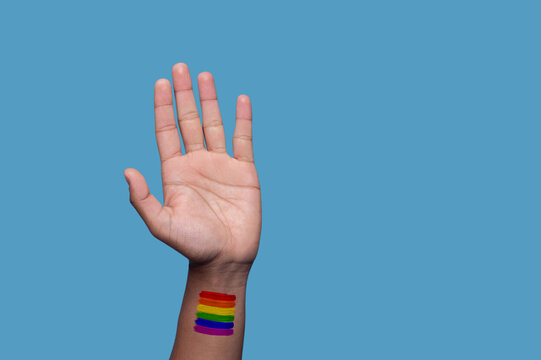 Person demonstrating the LGBTQ symbol against the blue background