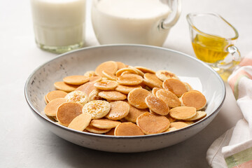 Pancake cereal or mini pancakes with honey in plate on concrete background