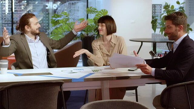 Cheering business people discussing documents in meeting