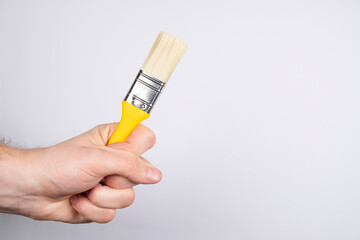 Clean paint brush on a white background. Man hand hold paintbrush